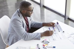 top-view-of-dark-skinned-african-male-copywriter-or-enterpreneur-looks-attentively-at-documents-stu-jpg